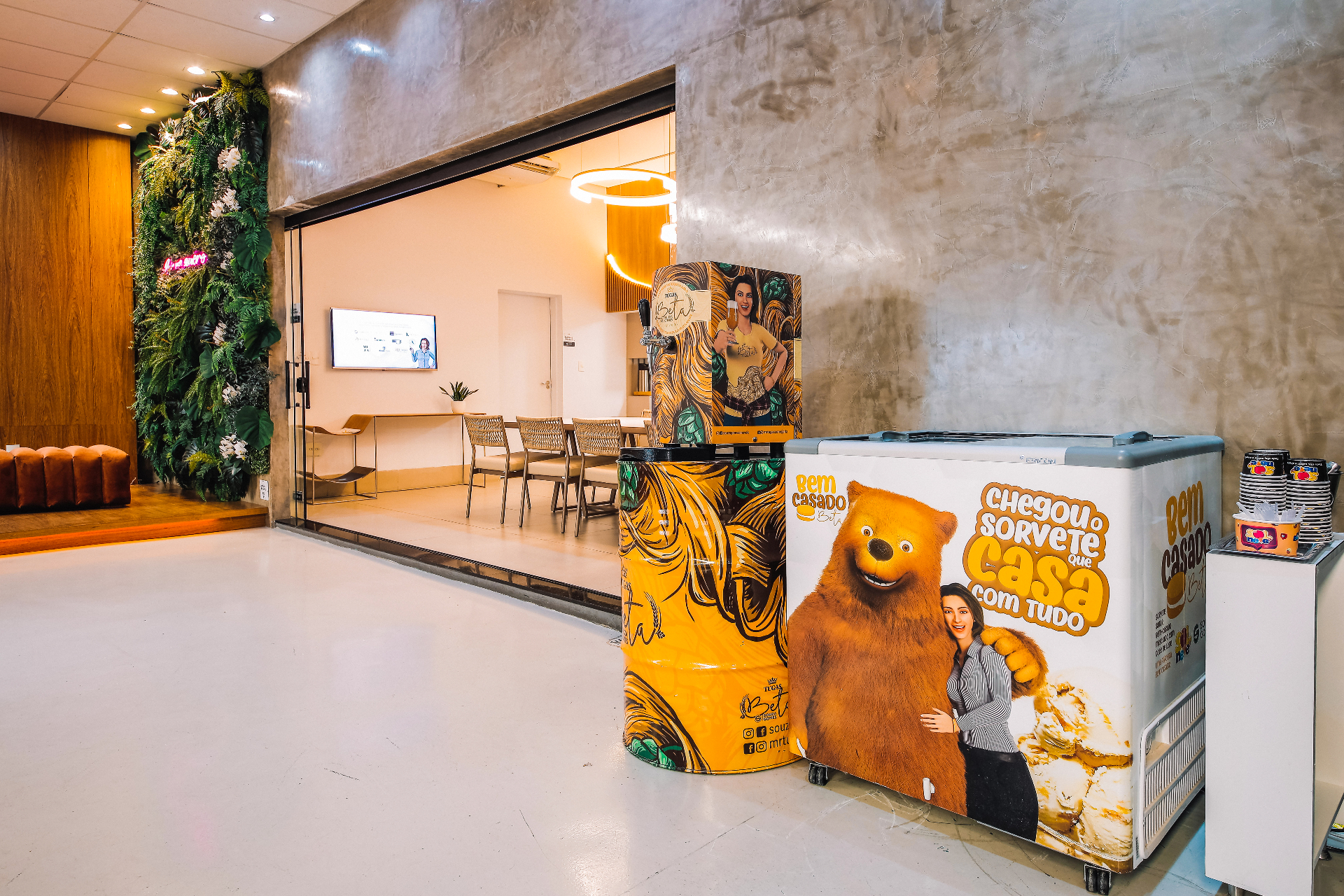 Entrada do Espaço Multi com jardim vertical, área lounge ao fundo e estrutura de bar